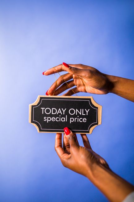 A person's hands with red-painted nails holding a small black and gold sign that reads 'TODAY ONLY special price' against a light blue background. The sign is framed with a decorative gold border and 